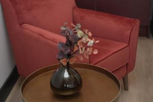 Un jarrón sobre una mesa frente a un sofá rojo. en The Sixty Aparthotel - Central Cardiff Apartment with Parking, en Cardiff