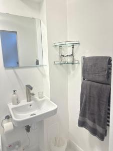 a white bathroom with a sink and a mirror at Unique space in Edgware in Stone Grove