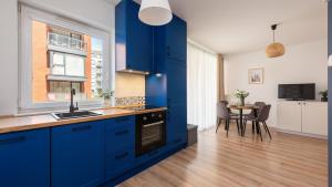 a kitchen with blue cabinets and a table with chairs at Flatbook - City Center Comfort Studio in Gdańsk