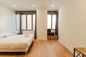 a bedroom with a bed and some windows at Le Chapelier in Valence