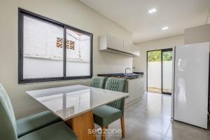 皮萨拉斯Casa c/ Churrasq. a 500 m da Praia CGE0003的厨房配有桌子和一些绿色椅子