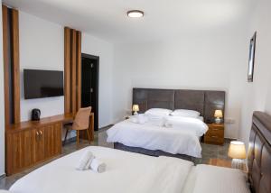 a hotel room with two beds and a flat screen tv at Suya Studios by HolidayKeys in Karavas +20 photos