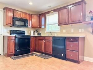 里士满Cozy Home on Golf Course Near I75 and Bucee's的厨房配有木制橱柜和黑色洗碗机。