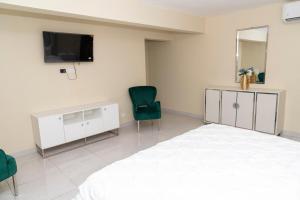 Un dormitorio con una cama y un televisor y dos sillas. en La Isla Royal - Abismo Celeste, en Miches