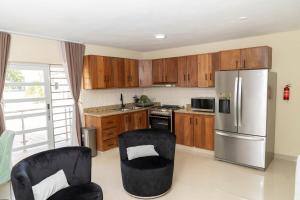 Una cocina con gabinetes de madera y un refrigerador de acero inoxidable. en La Isla Royal - Abismo Celeste, en Miches