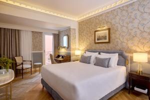 Un dormitorio con una cama blanca grande y un escritorio en Mediterranean Palace, en Tesalónica