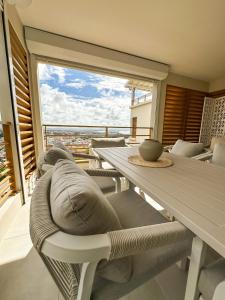 - un salon avec une table, des chaises et une grande fenêtre dans l'établissement Appartement Madinina View, à Fort-de-France