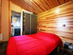 a red bed in a room with a wooden wall at PRL El Pastural in Err