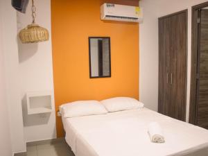 una camera con un letto bianco e una parete arancione di Casa gimani Betts a Cartagena de Indias