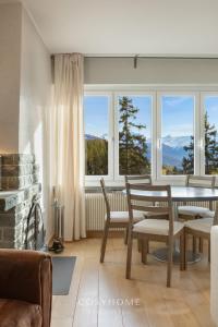 a living room with a table and chairs and windows at Alpine Sunset l Attique l Golf l By CosyHome in Crans-Montana +38 photos