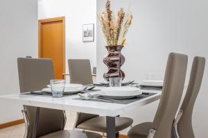 une table de salle à manger avec des chaises et un vase avec des fleurs dans l'établissement Parking & Free WiFi - Functional apartment, à Modène