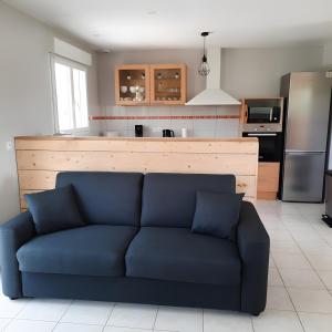 Una sala de estar con un sofá azul frente a una cocina. en Gîte avec salle de jeux, en Montfarville