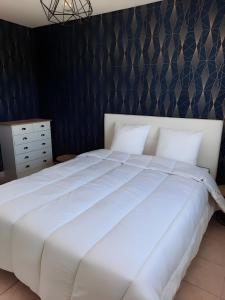 Una cama blanca en un dormitorio con una pared negra. en Gîte avec salle de jeux, en Montfarville