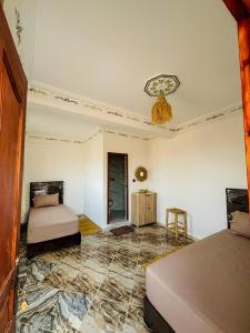 a room with two beds and a ceiling at Dar lkbira Azazoul in Taghazout