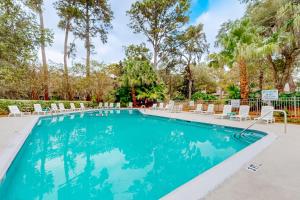 ein Swimmingpool mit Liegestühlen und Bäumen in der Unterkunft Racquet Club Villas 2327 in Hilton Head Island