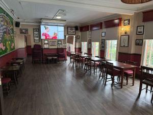 a dining room with tables and chairs and a screen at Twelfth Man Accommodation part of The Twelfth Man Public House in Liverpool