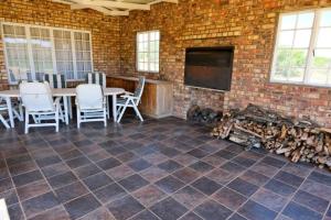 Habitación con mesa, sillas y pared de ladrillo. en Geluk Farmhouse, en Somerset East