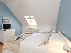 a bedroom with a white bed and a tv at Holiday Home Le Nid de Cancale by Interhome in Cancale