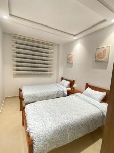 a bedroom with two beds and a window at Cozy apartment in Kenitra