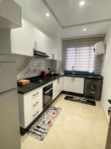 a kitchen with white cabinets and a stove top oven at Cozy apartment in Kenitra