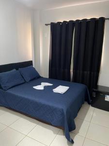 a bedroom with a blue bed with black curtains at Manancial Hotel in Paracatu