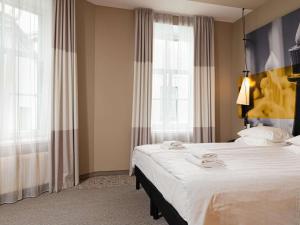 a bedroom with a large white bed and windows at Ibis Riga Centre in Riga