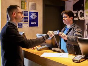 a man and a woman sitting at a table with a cash register at ibis budget SP Frei Caneca in Sao Paulo