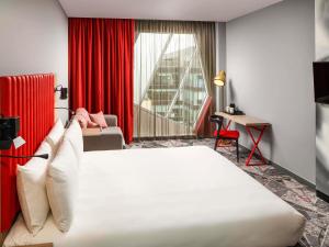 Habitación de hotel con cama y cortina roja en ibis Styles London Ealing, en Londres