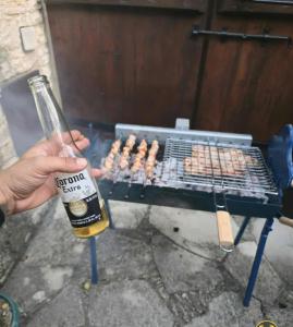 a person holding a bottle of beer next to a grill at Lοfou-Queen in Lofou