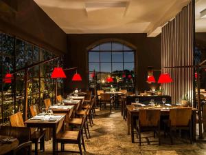 a restaurant with wooden tables and chairs and red lamps at Santa Teresa Hotel Rio de Janeiro - MGallery Collection in Rio de Janeiro