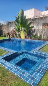 une piscine avec un palmier dans une cour dans l'établissement Casa Monã - Praia de Tatuamunha - Serviços Inclusos, à Porto de Pedras