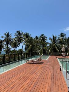 a wooden boardwalk with benches and palm trees in the background at Refugio a 50 passos do mar in Tamandaré