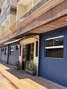 a blue building with potted plants in front of it at Manancial Hotel in Paracatu