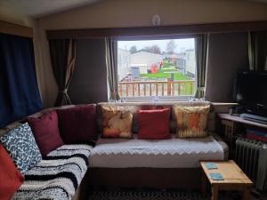 a living room with a couch with pillows and a window at Willows 104 Caravan - 7 Lakes in Crowle