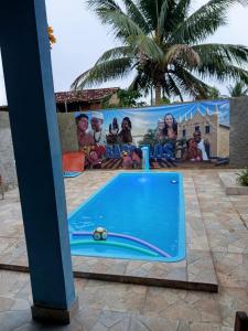 a swimming pool in front of a movie poster at Recanto Barcelos de Mel com piscina e churrasqueira in Camamu