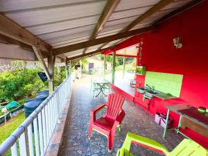 a patio with a red wall and a table and chairs at Maison de charme au Robert avec spa et vue sur mer in Le Robert