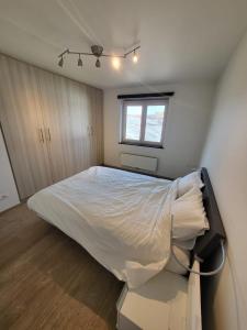 une chambre avec un lit blanc avec une fenêtre dans l'établissement Ruim appartement met terras, à Gand