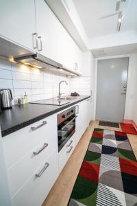 eine Küche mit weißen Schränken und einem bunten Teppich auf dem Boden in der Unterkunft Modern Studio in the Heart of Linné, Walk to Haga in Göteborg