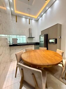 eine Küche und ein Esszimmer mit einem Holztisch und Stühlen in der Unterkunft Casa Luxo, 3 Qt, Piscina, 2 Vaga, e Área Gourmet in Palmas + 24 Fotos