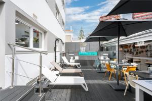 an outdoor patio with chairs and tables and an umbrella at Porta 30 in Oeiras