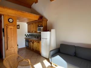 Il comprend une cuisine équipée d'un canapé et d'un réfrigérateur blanc. dans l'établissement Appartement Les Airelles, à Levassaix