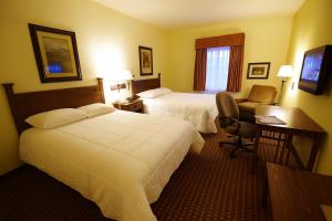 a hotel room with two beds and a desk and a chair at Mountain Inn & Suites Airport - Hendersonville in Hendersonville