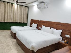 une chambre avec deux lits avec des draps blancs dans l'établissement Marquis Beach Resort, à Candolim