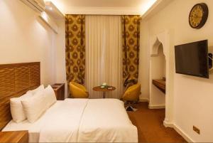 une chambre d'hôtel avec un lit blanc et une télévision dans l'établissement Marquis Beach Resort, à Candolim