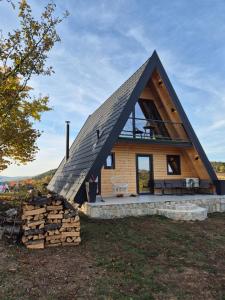 a house with a pitched roof with a pile of logs at Sunflower House Radoinja in Nova Varoš