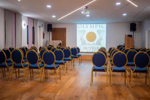a conference room with blue chairs and a stage at Olympic regina hotel in Pinzolo +34 photos