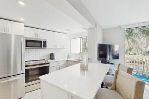 eine Küche mit weißen Schränken und einem Tisch mit Stühlen in der Unterkunft Seascape Villas 3040 in Hilton Head Island + 25 Fotos