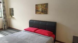 ein Bett mit zwei roten Kissen in einem Zimmer in der Unterkunft Warisan Indah Homestay KLIA 2 Melayu sahaja in Sepang
