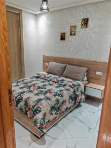 Un dormitorio con una cama con un edredón colorido. en Appartement idéal à El Jadida pour les familles, en Sidi Bouzid