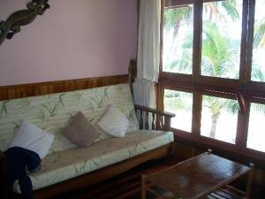 - un canapé dans une chambre avec 2 fenêtres et une table dans l'établissement Samara Tree House Inn Unit 4, à Sámara